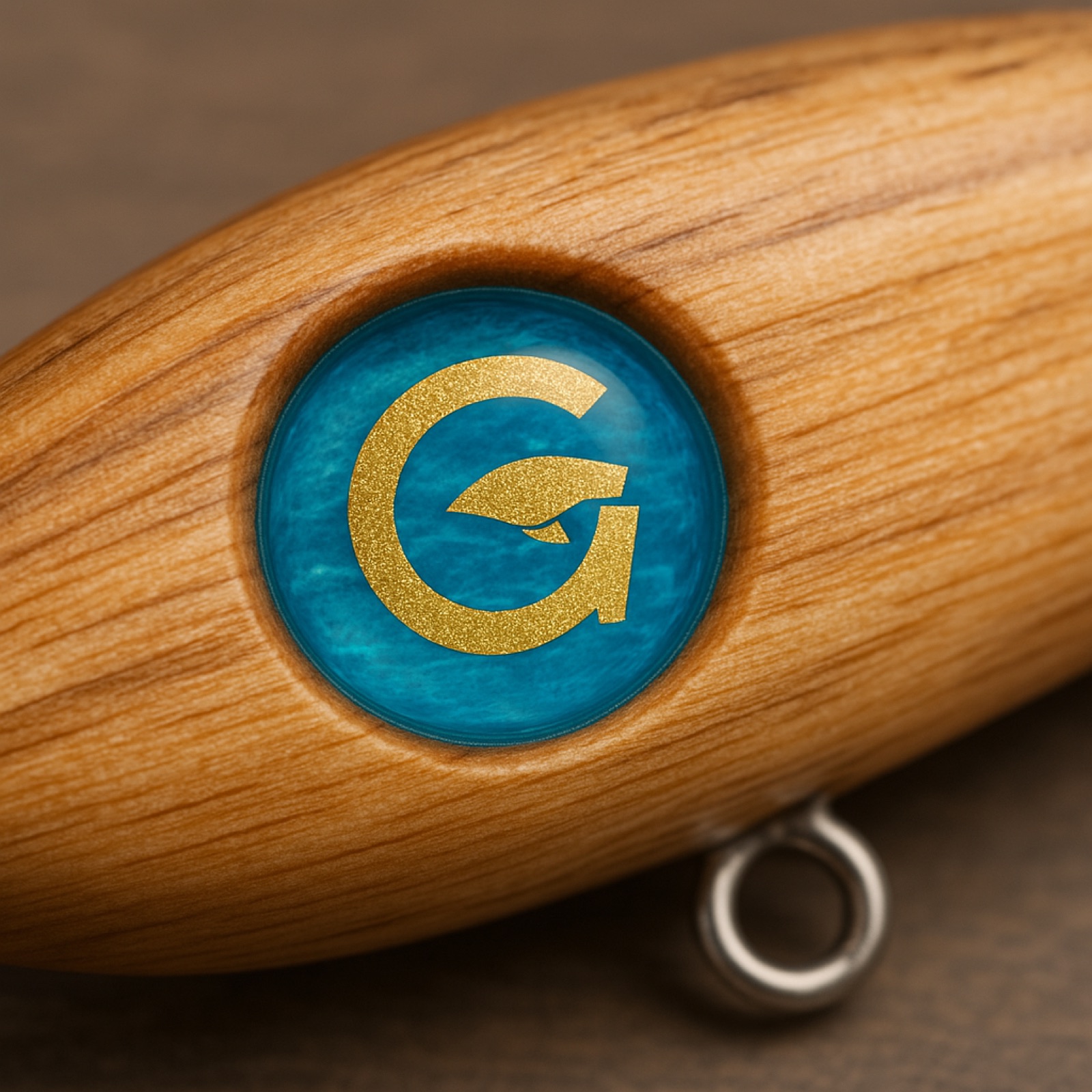 GOLDFISHINGのハンドメイドルアー。檜のボディに金のGを封じたレジンのエンブレム。